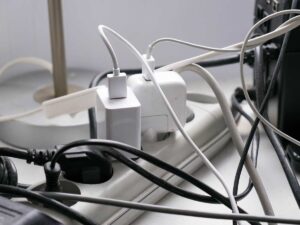 A cluttered power strip filled with tangled charging cables and multiple plugged-in devices, showing the urgency of charging during short periods of electricity availability in Nigeria.